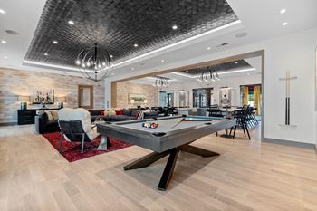 A billiard table is in the middle of a room with a chair and a pool table.